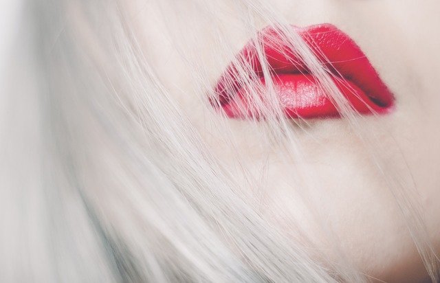 Ženská tvár s červenými perami prekrytými vlasmi.jpg